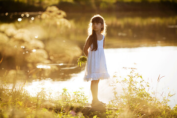 Girl stands on the shore of a small pond on a summer evening.