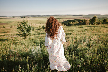 Young woman walking in summer field enjoying nature