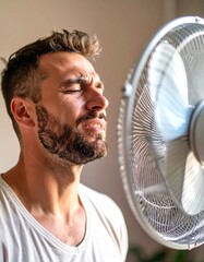 A person in front of a fan with an expression of feeling hot, trying to cool down a bit during the summer. Temperature, cool down, air, scorching