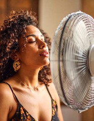 A person in front of a fan with an expression of feeling hot, trying to cool down a bit during the summer. Temperature, cool down, air, scorching