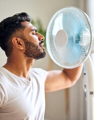 A person in front of a fan with an expression of feeling hot, trying to cool down a bit during the summer. Temperature, cool down, air, scorching