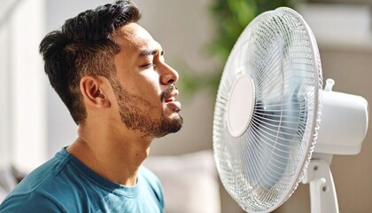 A person in front of a fan with an expression of feeling hot, trying to cool down a bit during the summer. Temperature, cool down, air, scorching