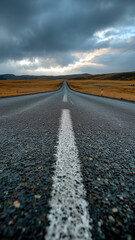 Solitary Road:  A long road stretches to the horizon beneath a dramatic sky. An asphalt path across an open landscape.
