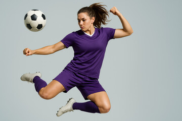 Fototapeta premium Soccer Player in Mid-Air Kick: A female soccer player in a purple uniform executes a powerful mid-air kick, demonstrating athleticism and skill. The dynamic pose showcases her determination and focus.