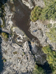 Aerial View of Rocky Riverbed with Person Sitting on Boulder