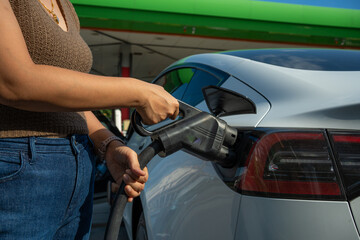 Smart business asian woman hand use ev car charge in ev station travel trip