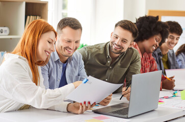 Team of happy business people working together on paperwork and a laptop during a meeting in the...