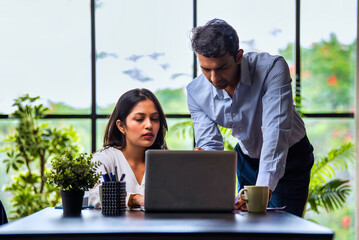 Indian businessmen Working on laptop and reviewing project papers together at desk in indoor office