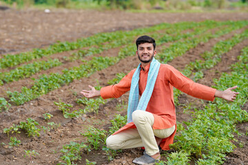young indian farmer working in green agricultural field