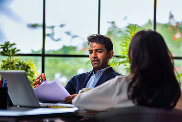 Interviewing job applicant across desk with laptop, Indian businessman meets female candidate