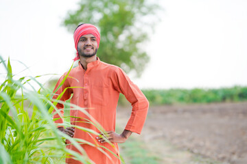 young indian farmer standing at green agriculture field