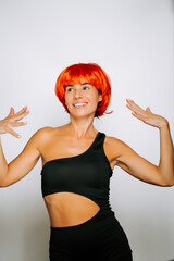 Woman with bright red wig poses confidently in black athletic wear against a plain background