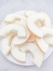 Slices of korean melon arranged on white plate, refreshing summer treat