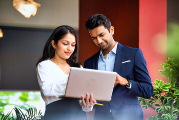 Walking indoors celebrating with laptop, Indian business team cheers with energy and confidence