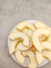 Sliced melon pieces arranged on white plate, refreshing summer fruit platter
