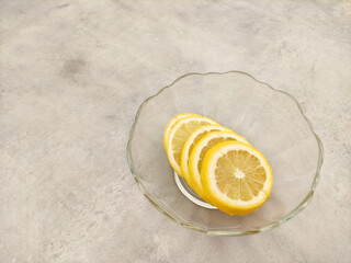 Lemon slices resting in a glass bowl on a marble countertop