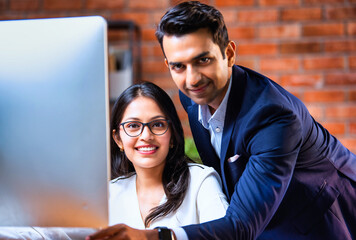 Indian team using computer in modern office with exposed brick wall and teamwork focus