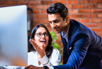 Indian team using computer in modern office with exposed brick wall and teamwork focus
