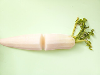 Fresh white radish in isolated on aoft green pastel background.
