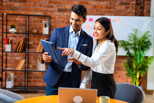 Chasing project deadline indoors, Indian corporate team discusses work using tablet in office