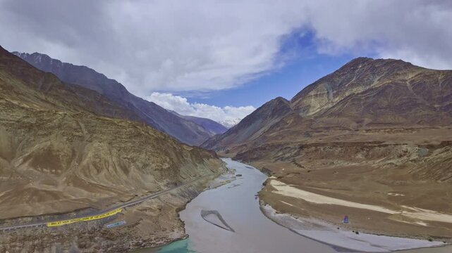The confluence of the Indus and Zanskar rivers has two different colors of water between Kargil and Leh, India. The scene beautifully showcases a dramatic, arid mountain landscape