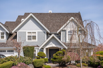 Two story stucco luxury house with nice spring blossom landscape in Vancouver, Canada, North America. Day time on June 2025.