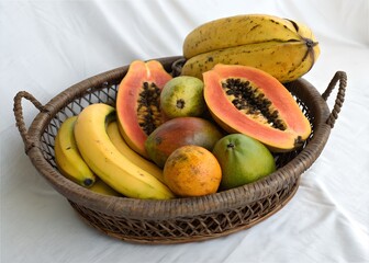 Papaya and mixed fruits in traditional basket on white background