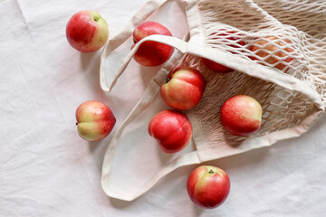 Nectarine. Ripe juicy organic nectarines (peaches) in a reusable mesh cotton shopping bag. plastic...