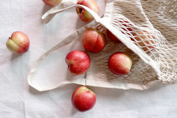 Nectarine. Ripe juicy organic nectarines (peaches) in a reusable mesh cotton shopping bag. plastic...
