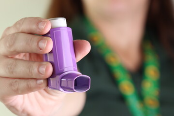 Woman worker holding a asthma device when wearing a hidden disability lanyard