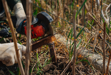 A man cuts off a piece of metal with a grinder. The power tool is in the hands of the master. Construction works.