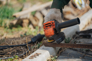 A man cuts off a piece of metal with a grinder. The grinder is in the hands of a master. Construction works.