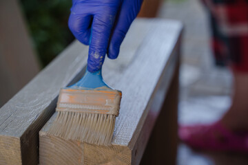 The process of gray painting a wooden step. A woman paints a wooden product. Paint a wooden shelf with acrylic.