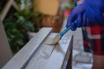 The process of gray painting a wooden step. A woman paints a wooden product. 