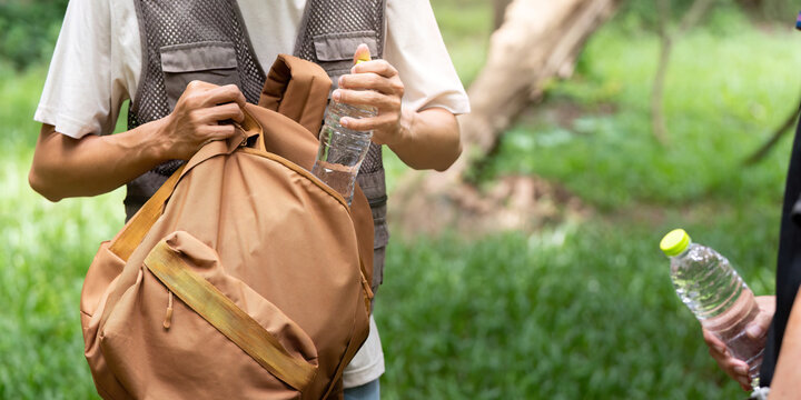 Hiking Essentials: Young Man Packing Water Bottles in Backpack