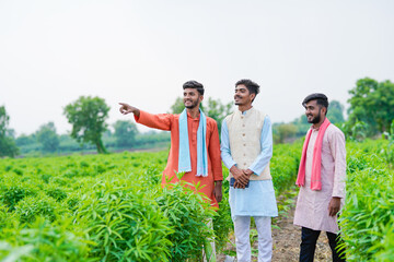 young indian farmer group standing together at green agricultural field