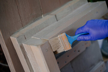 The process of gray painting a wooden step. A woman paints a wooden product. 