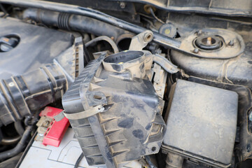 An open car air filter housing reveals engine components, indicating ongoing maintenance or repair....