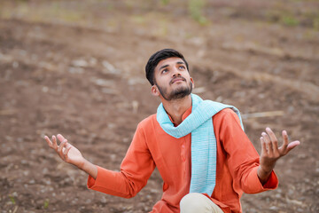 young indian farmer sitting agricultural field