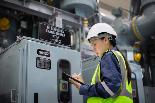 Engineer inspects gas insulated switchgear equipment carefully while taking notes in industrial setting ensuring safety and functionality of electrical system