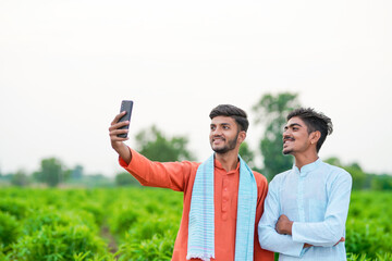 two young indian farmer taking selfie in green agricultural field