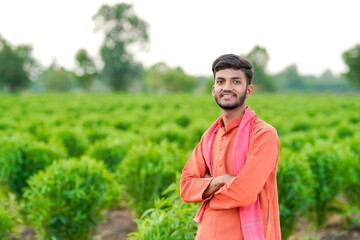 young indian farmer standing at green agricultural field