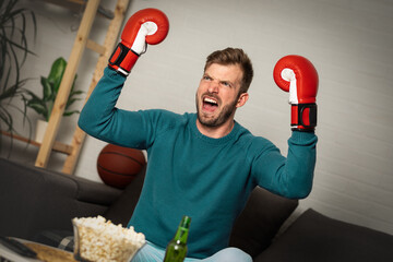Happy boxing fan celebrating victory in living room