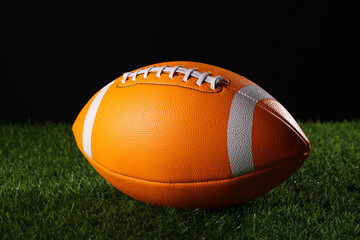 A textured American football resting on the green artificial turf with white line. College Football