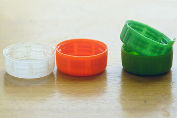 Close-up of several multi-colored plastic caps on wooden table – a metaphor for waste sorting...