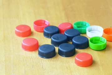Colorful plastic bottle caps arranged on wooden surface. Concept of waste sorting, sustainable...