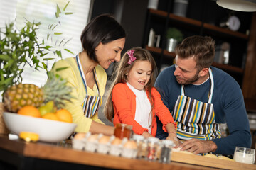 Little girl baking delicious pastry with her parents