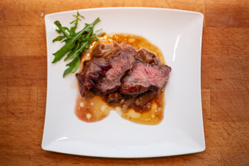 Freshly sliced steak served on plate with fresh herbs, gourmet meat presentation
