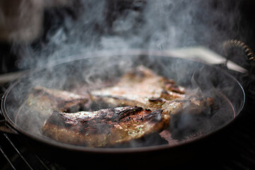 Smoky steak cooking on barbecue grill with smoke, juicy grilled beef without flames