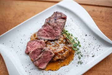 Freshly sliced steak served on plate with fresh herbs, gourmet meat presentation
